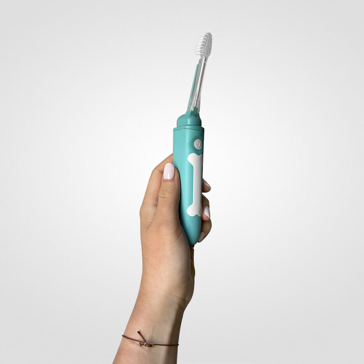 Hand holding a teal electric toothbrush with a bone design.